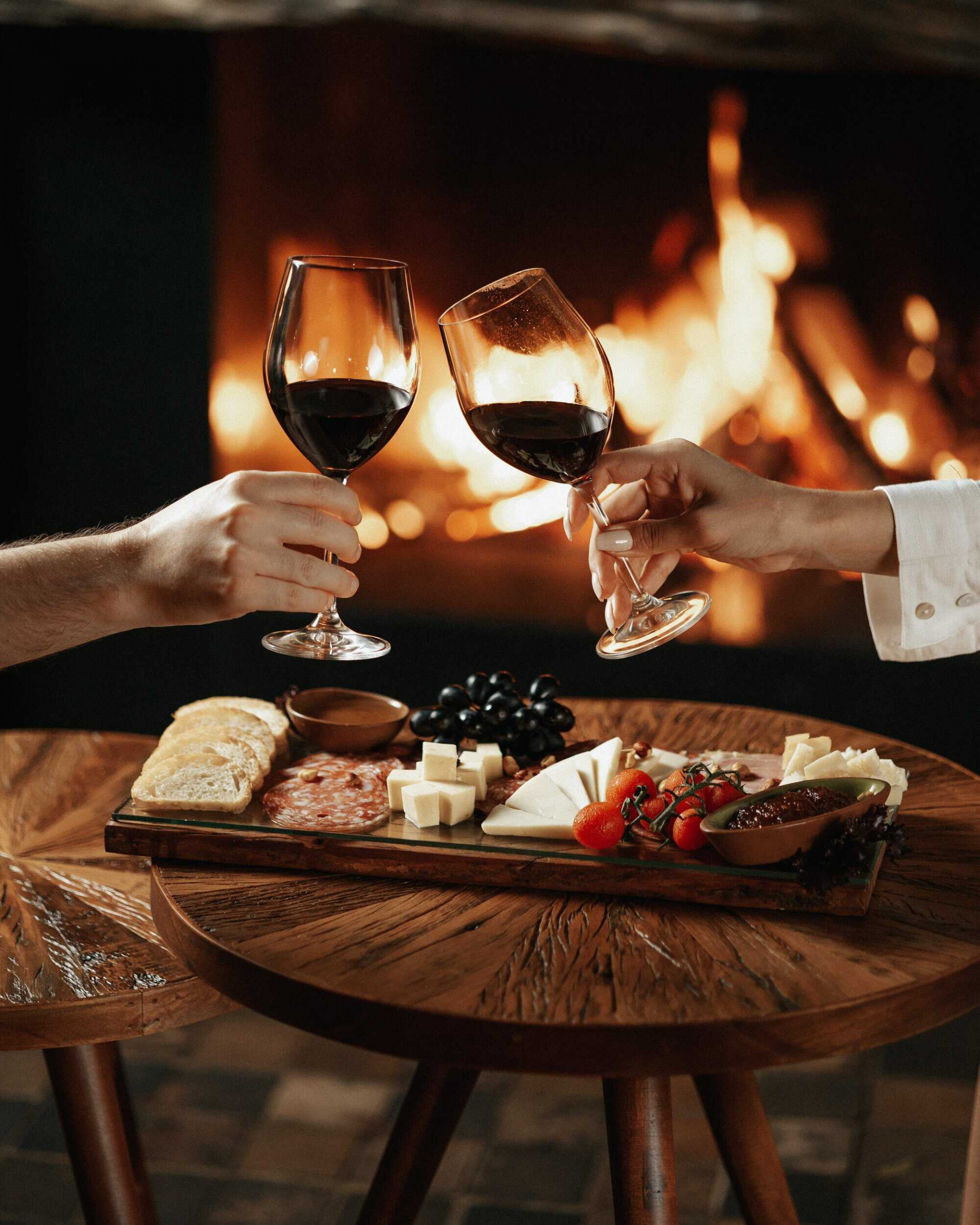 Copas de vino y tabla de quesos al lado de la chimenea en LAS Wine Bar en LAS Boutique Hotel